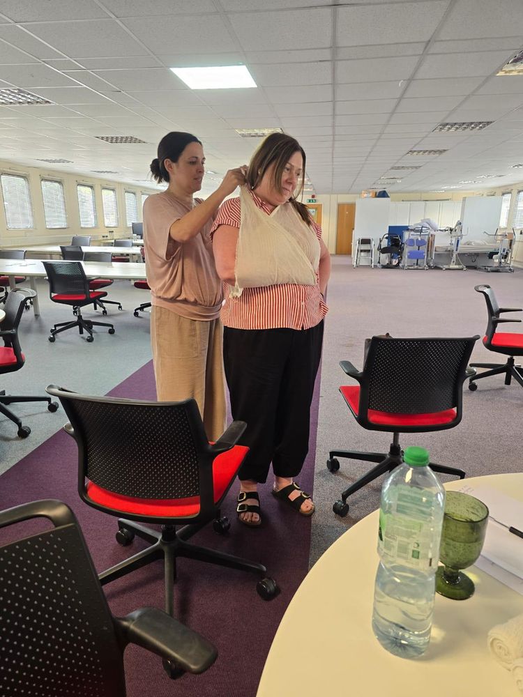 Trainer demonstrating how to apply an arm sling during a first aid course